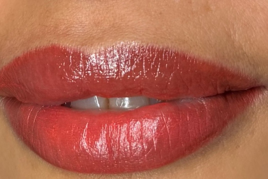 Lippen met permanente make-up in warm rood